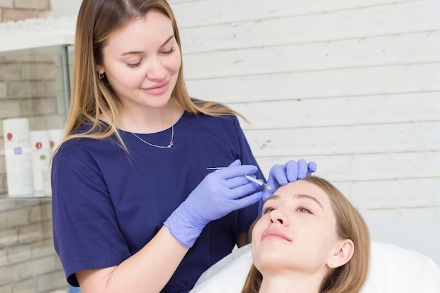 The cosmetologist gives injections to the girl