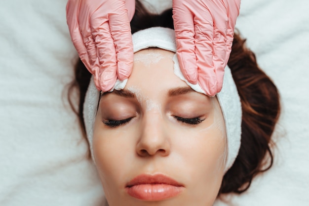 Cosmetologist giving a facial massage to a woman with sponge and gloves