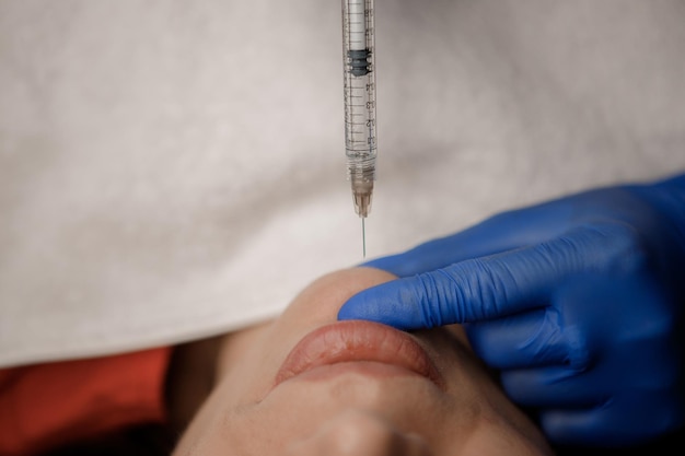 A cosmetologist injects a syringe into a patient