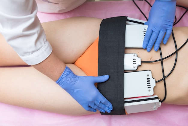 The cosmetologist installs the massage machine on the client