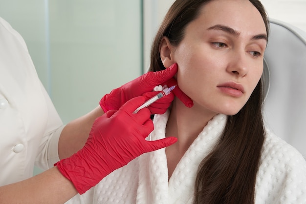 Cosmetologist makes lipolytic injections to burn fat on the chin against double chin.