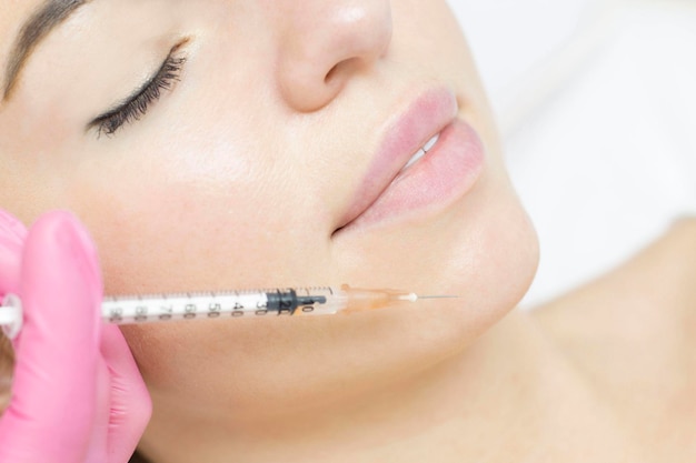 A cosmetologist makes lipolytic injections to burn fat on a woman's face prp therapy on the face