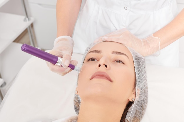 Cosmetologist makes mesotherapy injection for rejuvenation woman face procedure in beauty salon