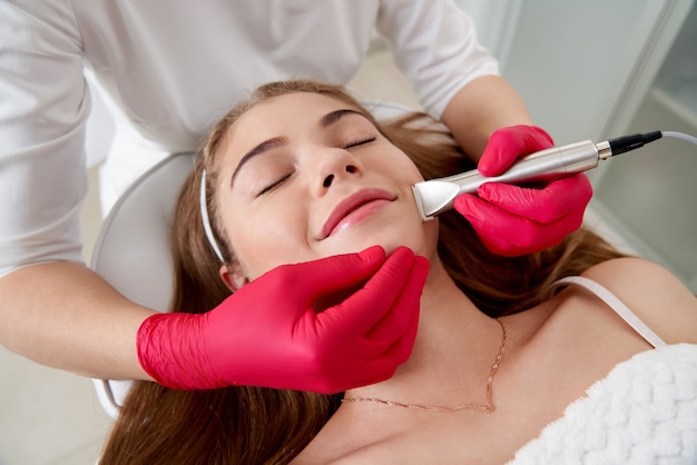 Cosmetologist making hardware cleaning of the face of beautiful young patient concept skin cleansing