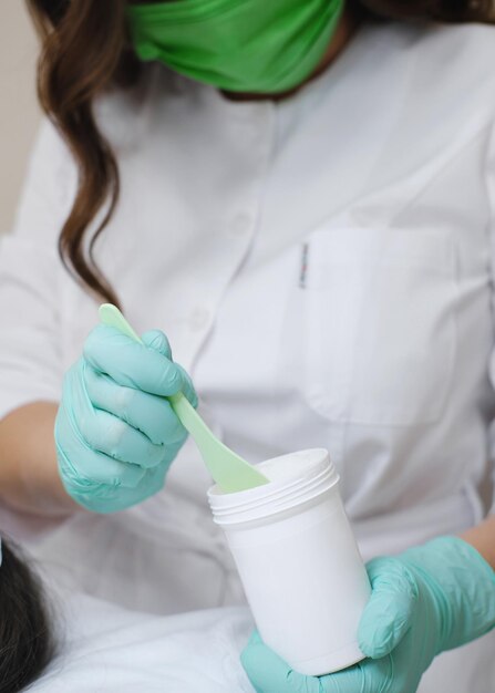 Cosmetologist Preparing Mask with Spatula for Facial Treatment