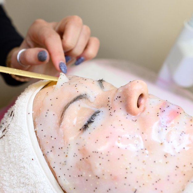 A cosmetologist removes a moisturizing sheet mask on a woman's face cosmetology procedures