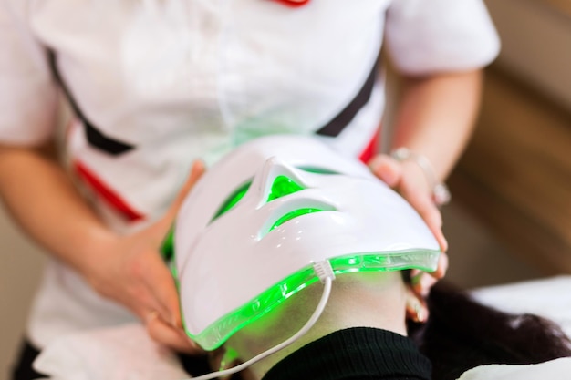 Cosmetologist Securing LED Therapy Mask on Client