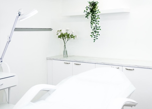 cosmetology cabinet interior with white cosmetology chair, white walls and flowers