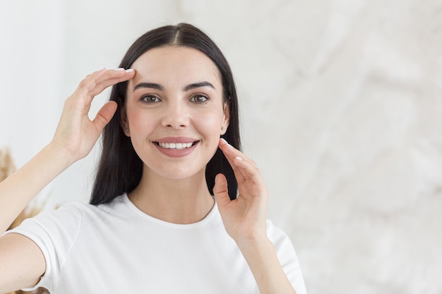 Cosmetology closeup portrait of young beautiful brunette woman with clean white skin he gently