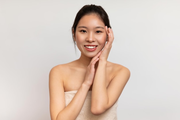 Cosmetology and skin care concept portrait of young korean lady holding her hand near face and