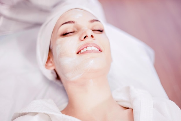 Cosmetology Smiling girl on procedure with mask applied to face Visiting cosmetology clinic