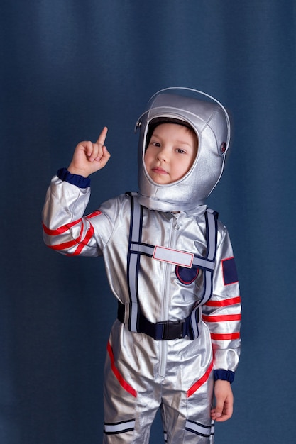 cosmonaut concept portrait of little boy in cosmonaut costume and helmet with raised forefinger up