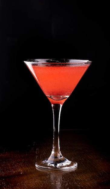 Cosmopolitan cocktail in martini glass on wooden table front view