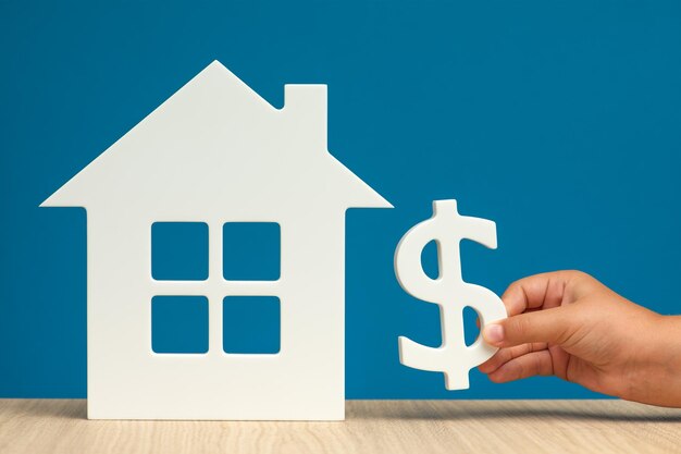 The cost of renting real estate in the USA Renting residential real estate in America Model of a white house and a hand with a dollar symbol on a blue background closeup copy space