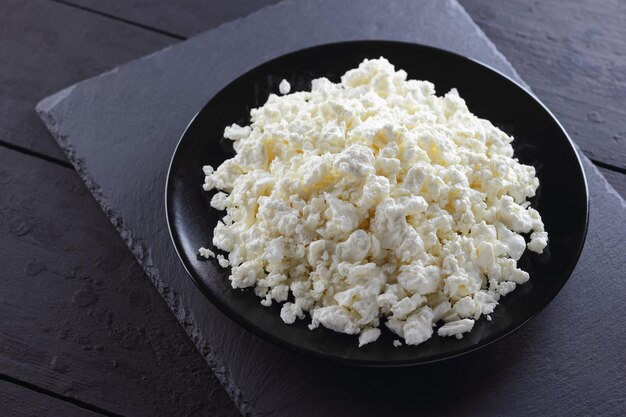 Cottage cheese on black slate board Fresh cottage cheese on black plate Soft cheese