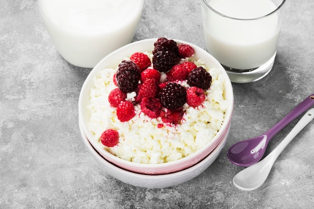 Cottage cheese in bowl with frozen raspberry and blackberry and milk in glass  