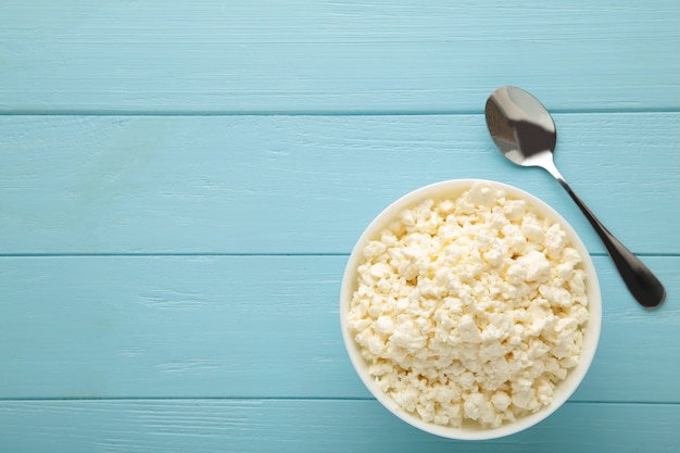 Cottage cheese for breakfast in bowl on blue background. Top view