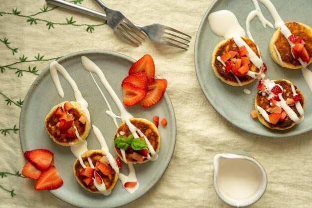 Cottage cheese cakes with strawberries and sour cream on plates breakfast table high quality photo top view