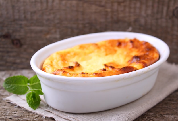 Cottage cheese casserole in white dish, on a blue background