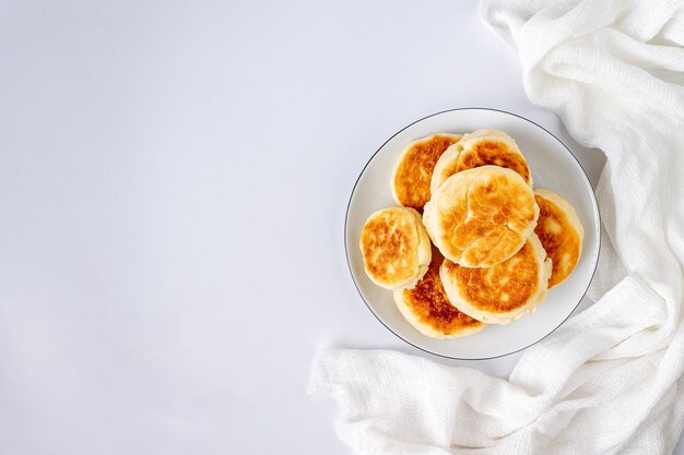 Cottage cheese cheesecakes lie in a white ceramic plate on a white background with copy space