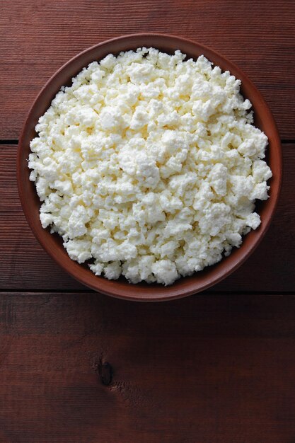 Cottage cheese in clay plate on wooden boards Soft cheese on wooden background Close up