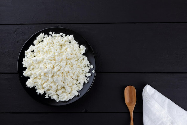 Cottage cheese on dark wooden background Soft cheese on black plate Copy space