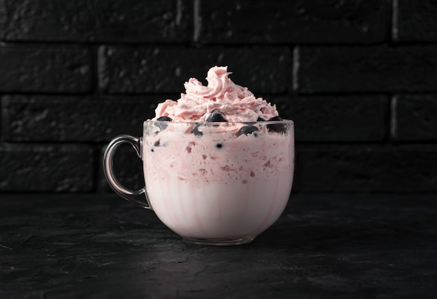 Cottage cheese dessert with cream and berries on a black table.