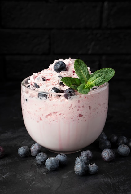 Cottage cheese dessert with cream and berries on a black table.