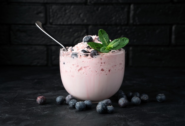 Cottage cheese dessert with cream and berries on a black table.