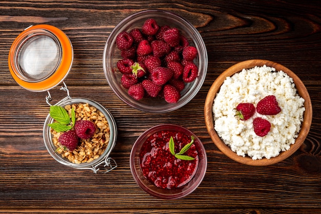 Cottage cheese, granola and fresh raspberry on dark wooden background