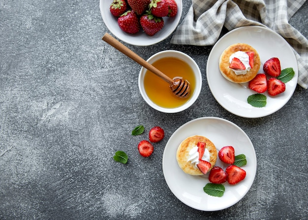 Cottage cheese pancakes, ricotta fritters on ceramic plate with  fresh strawberry. Healthy and delicious morning breakfast.