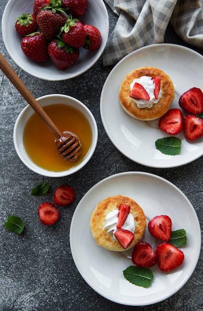 Cottage cheese pancakes, ricotta fritters on ceramic plate with  fresh strawberry. Healthy and delicious morning breakfast.