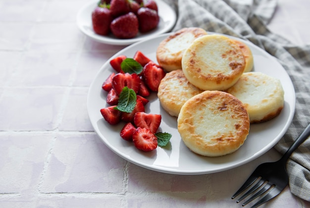 Cottage cheese pancakes ricotta fritters on ceramic plate with  fresh strawberry