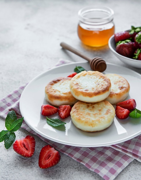 Cottage cheese pancakes ricotta fritters on ceramic plate with  fresh strawberry