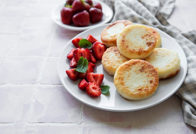 Cottage cheese pancakes ricotta fritters on ceramic plate with  fresh strawberry