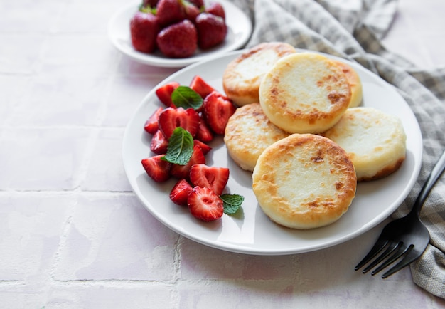 Cottage cheese pancakes ricotta fritters on ceramic plate with  fresh strawberry