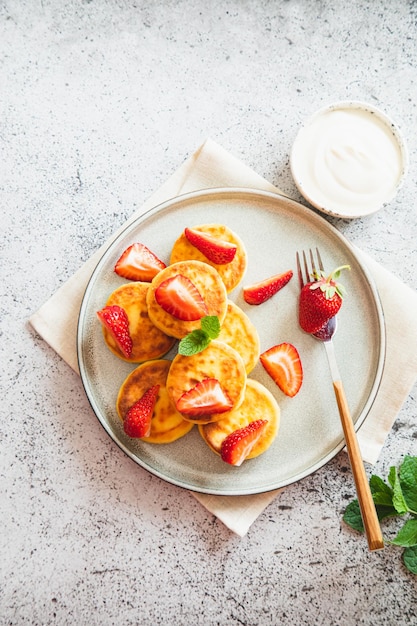 Cottage cheese pancakes ricotta fritters or syrniki with mint and strawberries Healthy and delicious morning breakfast