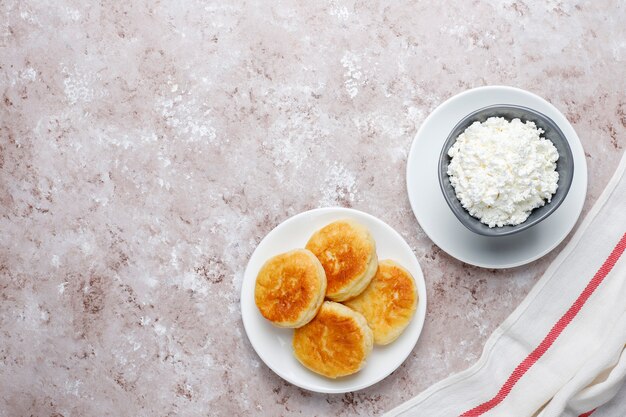 Cottage cheese pancakes.Russian syrniki or sirniki, cottage cheese fritters or pancakes with a bowl of fresh homemade cottage cheese