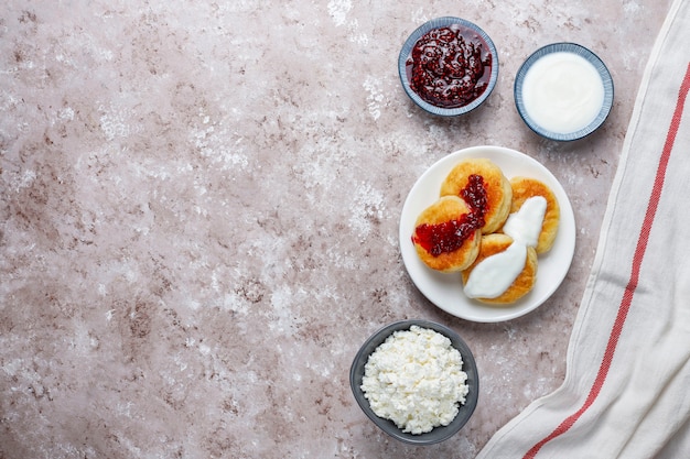 Cottage cheese pancakes.Russian syrniki or sirniki, cottage cheese fritters or pancakes with a bowl of fresh homemade cottage cheese