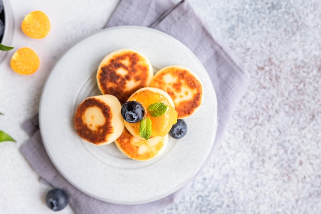 Cottage cheese pancakes sweet curd fritters with blueberry and physalis Syrniki with jam and berries