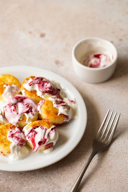 Cottage cheese pancakes syrniki ricotta fritters on white ceramic plate with sour cream and jam Healthy and delicious morning breakfast Beige background Food for kids