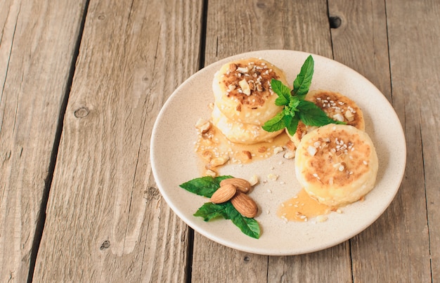  cottage cheese pancakes with almonds mint and maple syrup in a beige plate.