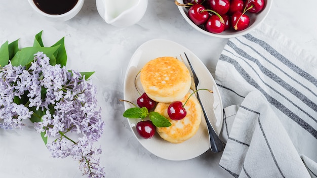 Cottage cheese pancakes with berry cherry, cup of black coffee