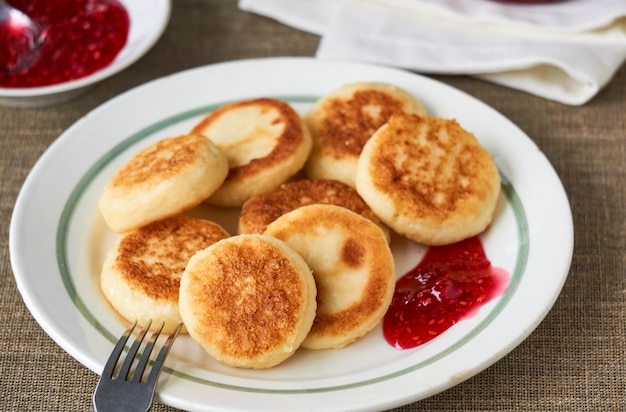 Cottage cheese pancakes with raspberry jam on a white plate