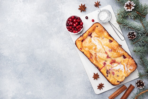 Cottage cheese pie casserole with cranberries and spices sprinkled with powdered sugar on a wooden stand