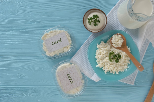 Cottage cheese in plastic packaging and milk on a wooden blue background Healthy eating concept