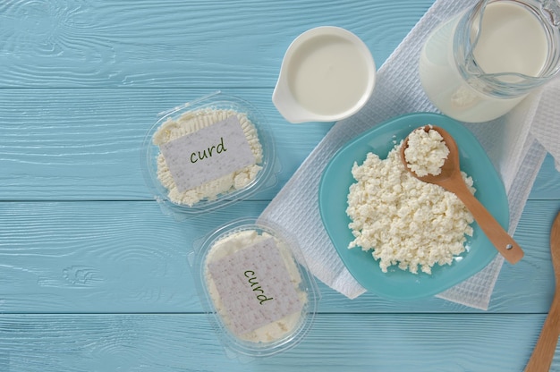 Cottage cheese in plastic packaging and milk on a wooden blue background