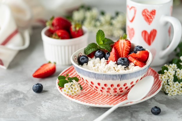 Cottage cheese with berries, jam, fresh strawberries and a cup of coffee with cream for breakfast.