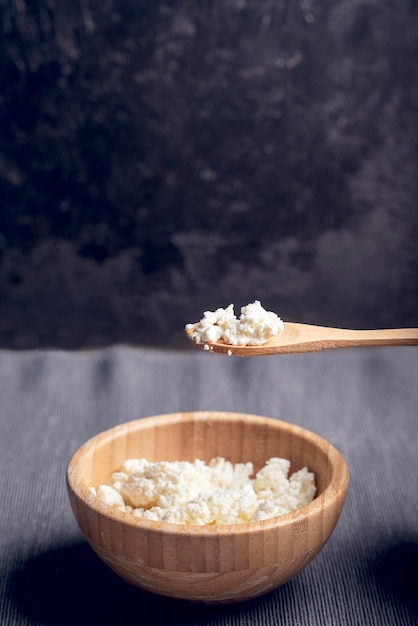 Cottage cheese in wooden bowl dark background