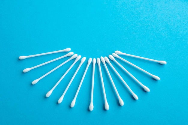 Cotton ear swabs sticks on blue background close up Image with selective focus noise effect and toning Top view Flat lay